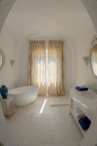 a white bathroom with a tub and a large window at Home Mykonos lux in Casoria