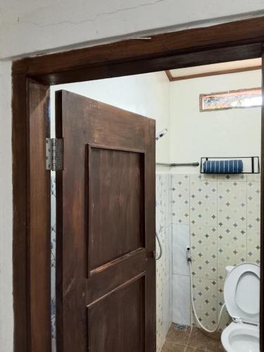 a bathroom with a wooden door and a toilet at Cendana Guesthouse Labuan Bajo2 in Labuan Bajo