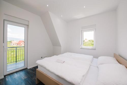a white bedroom with a bed and a window at Vila Paola in Kupres