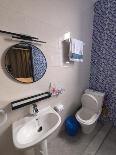 a bathroom with a sink and a toilet and a mirror at KIGALI E6 APARTMENTs RESORTS in Kigali