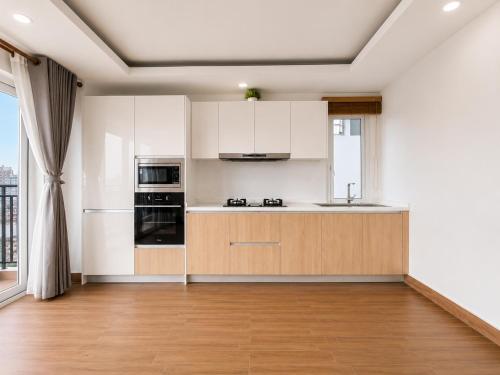 an empty kitchen with white walls and wooden cabinets at Sopor Resident in Phnom Penh