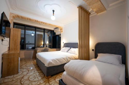 a hotel room with two beds and a television at COLFA STAR Hostel in Bejaïa