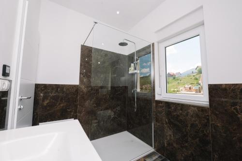 a bathroom with a shower and a window at Vila Paola in Kupres