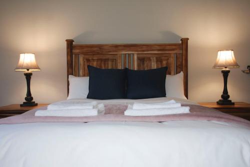 a bed with two lamps and towels on it at Tooiselvere in George