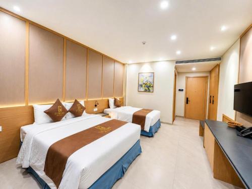 a hotel room with two beds and a television at Luxury 79 Hotel Hải Phòng in Hai Phong