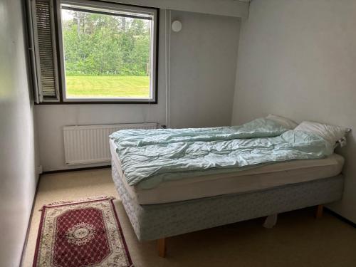 a bedroom with a bed with a window and a rug at Rivitalo 2 in Loimaa