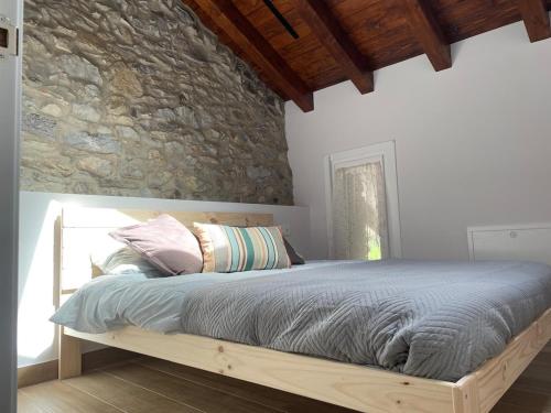a bed in a bedroom with a stone wall at Altxerri Baserria in Aia