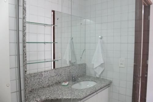 ein weiß gefliestes Badezimmer mit Waschbecken und Spiegel in der Unterkunft Nannai Residence - Muro Alto in Porto De Galinhas