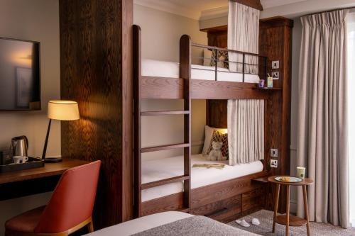 a bedroom with two bunk beds with a desk and a bed at Thorpe Park Hotel and Spa in Leeds