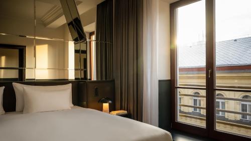 ein Schlafzimmer mit einem Bett und einem großen Fenster in der Unterkunft Almanac X Alcron Prague in Prag