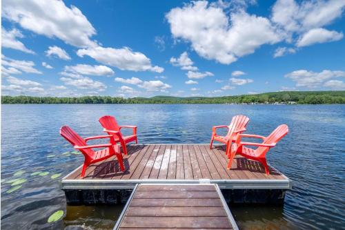 three red chairs sitting on a dock on a lake at Chalet Mid-Century - Lakeside Joseph - Le Charlo in Saint-Pierre-Baptiste