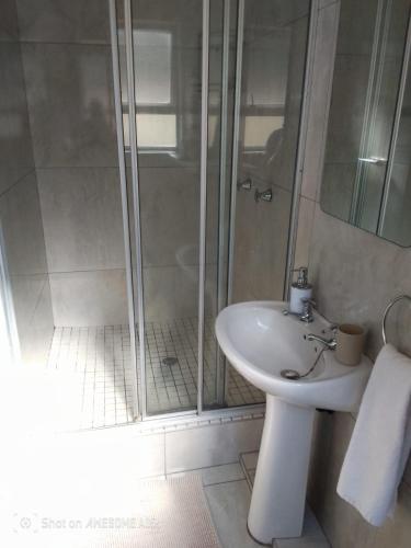 a white bathroom with a shower and a sink at 1 Seabreeze Cottage in Durban