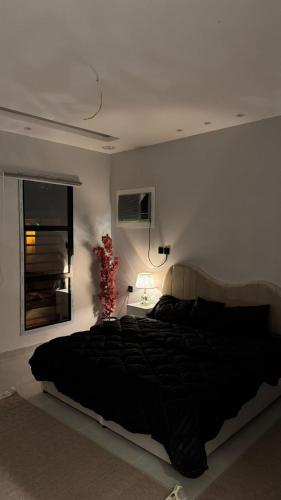 a bedroom with a large black bed and a window at شاليه in Al Baha