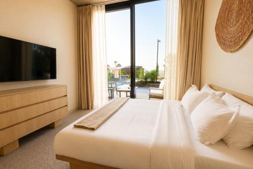 a bedroom with a bed with a television and a balcony at Inanna Resort in Kifrayyā