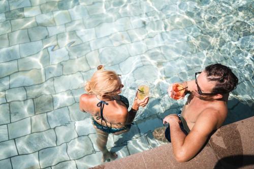 a man and a woman sitting in a swimming pool at Hotel Gartenresidence Zea Curtis in Merano