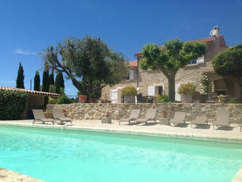 une piscine avec des chaises et une maison en arrière-plan dans l'établissement Bastide de Fontvieille, à Saint-Cyr-sur-Mer
