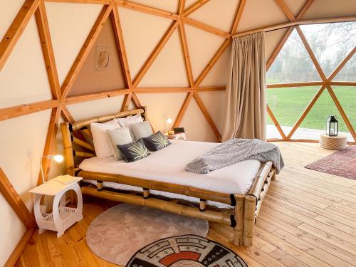 a bed in a room with a large window at Les Etangs de la Bassée in Gravon