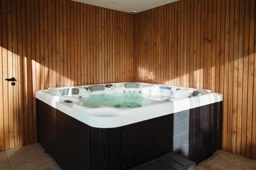 a large bath tub in a room with wooden walls at Les Etangs de la Bassée in Gravon