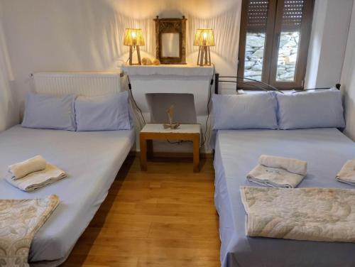 two beds in a room with a table and a mirror at Eternal blue in Volos