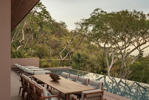a patio with a wooden table and chairs and trees at One&Only Mandarina in Lo de Marcos