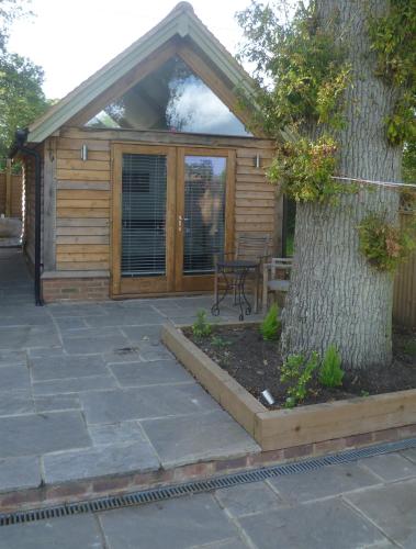 a wooden cabin with a table and a tree at Little Oak - Small Rural Self Contained Oak Barn Unit - Sleeps 2 in Haslemere