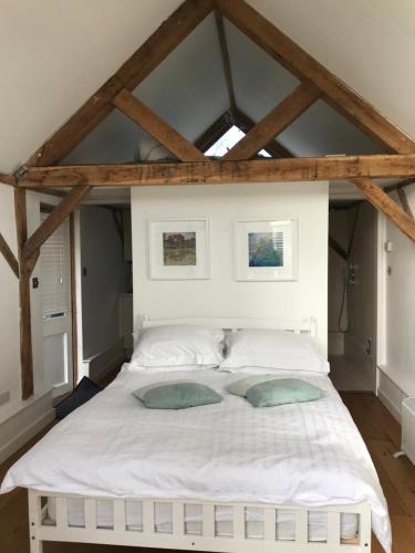 a bedroom with a white bed with two pillows at Little Oak - Small Rural Self Contained Oak Barn Unit - Sleeps 2 in Haslemere