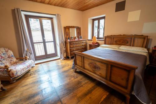 a bedroom with a bed and a chair and a window at Casa Ferrero - appartamenti in Paesana