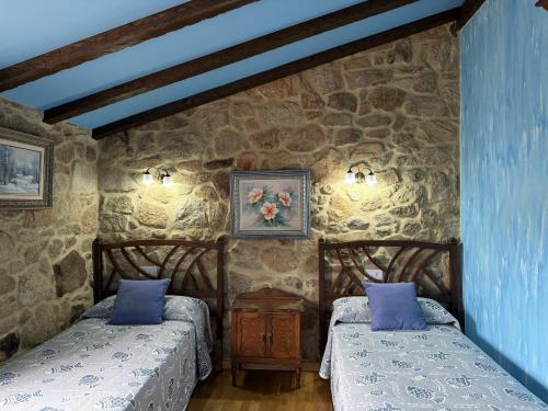 two beds in a room with a stone wall at BLEU MAISON-PAZO 1 CL in Campo Lameiro