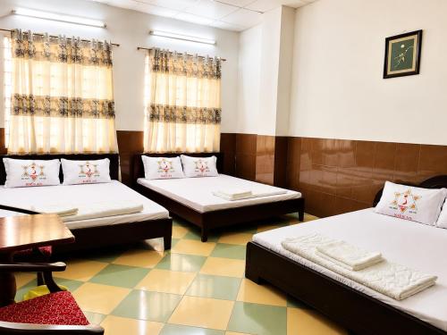 a room with two beds and a table at Kiến An Hotel Cần Thơ in Can Tho