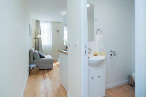 uma casa de banho branca com um lavatório e um espelho em Little River View Triplex in Alfama em Lisboa