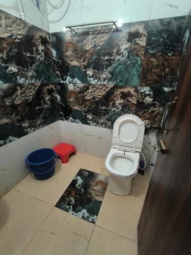 a bathroom with a toilet with a painting on the wall at Hotel Tokyo in Bathinda