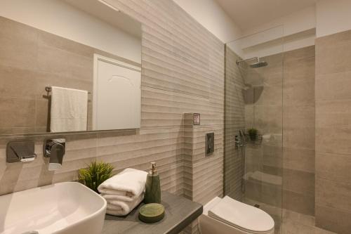 a bathroom with a sink and a toilet and a mirror at Ionian Dreaming in Lourdata