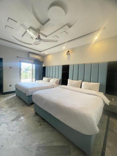 two beds in a hotel room with avertisement for at Aban Guest House in Peshawar
