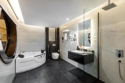 a bathroom with a tub and a sink and a toilet at فندق اورا ميلينيوم in Al Maraghah