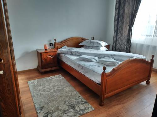 a bedroom with a wooden bed and a wooden floor at Pensiunea Casa Nușa in Baia de Fier