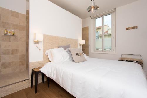 une chambre blanche avec un grand lit et une fenêtre dans l'établissement Budin Sea Cannes, à Cannes