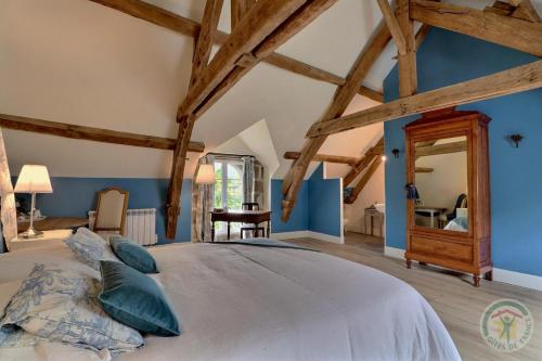 a bedroom with a large bed with blue walls and wooden beams at La bremande in Saint-Georges-de-Reintembault