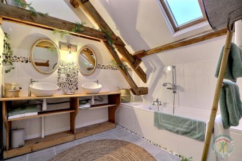 a bathroom with two sinks and a tub and mirrors at La bremande in Saint-Georges-de-Reintembault