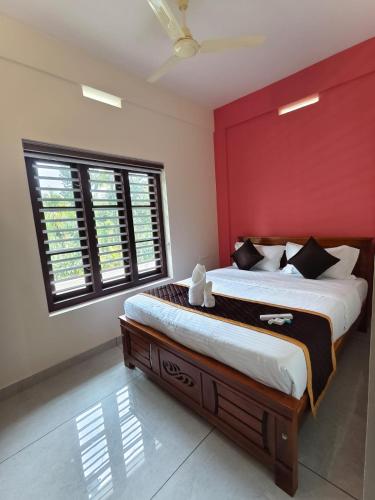 a bedroom with a large bed with a red wall at Havens Nature Homestay in Ambalavayal