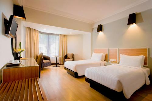a hotel room with two beds and a desk at Hotel Santika Premiere Jogja in Yogyakarta
