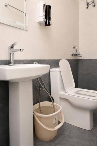 a bathroom with a toilet and a sink and a bucket at Hotel Vilasa Grand in Guwahati
