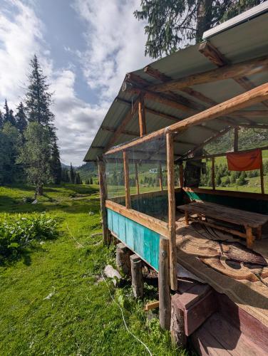 a wooden building with a porch in a field at Altyn Sky in Mineralʼnyy Istochnik Altyn-Arasan