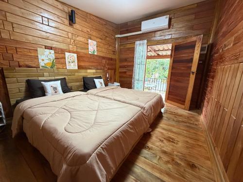 a bedroom with a large bed in a room with wooden walls at บ้านไม้ชายแดนกาแฟสดแอนด์โฮมสเตย์ in Ban Ba Nam Ron