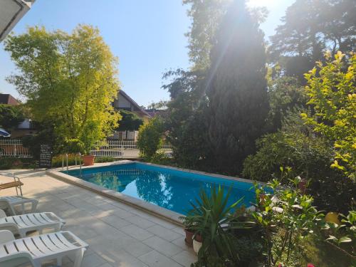 a swimming pool in a yard with chairs and trees at Aquasol Apartman in Siófok