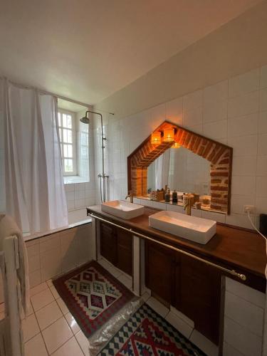 a bathroom with two sinks and a large mirror at Château la Gineste - Castle and Vineyard in Duravel