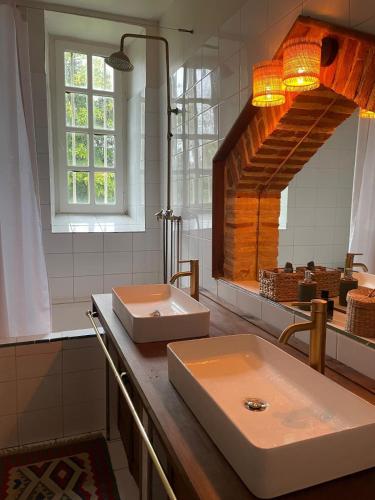 a bathroom with two sinks and a large mirror at Château la Gineste - Castle and Vineyard in Duravel