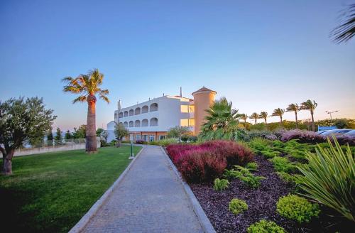 a building with a palm tree and a sidewalk at Hotel Maritur - Adults Only by Pierre & Vacances in Albufeira