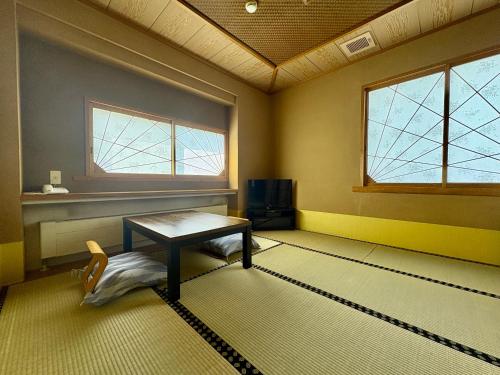 an empty room with a table and a window at Pension Puutaro in Zaō Onsen
