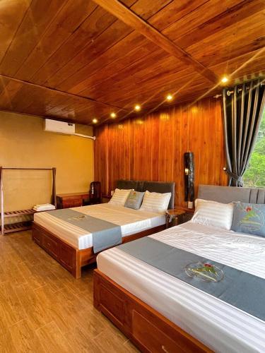 two beds in a room with wooden walls at HagiangHillside in Ha Giang