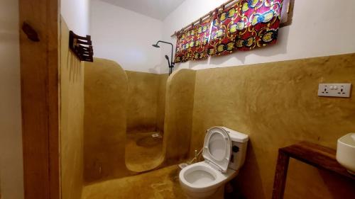 a bathroom with a toilet and a sink and a window at Raphy Home in Nungwi